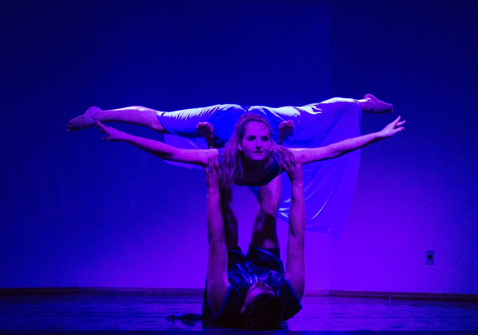 Dupla de bailarinos em pose sob luz azul no palco