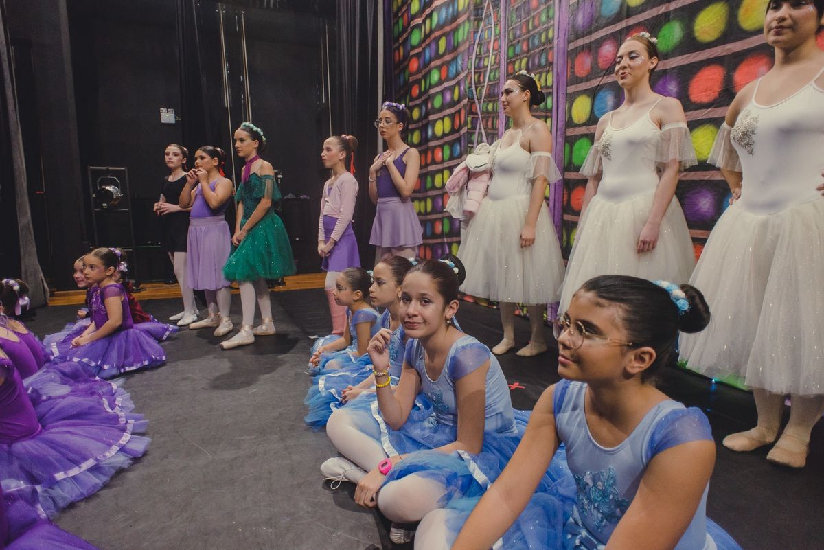 Turmas da Brilhart reunidas nos bastidores, de figurinos lilás, azul e branco, antes de entrar no palco