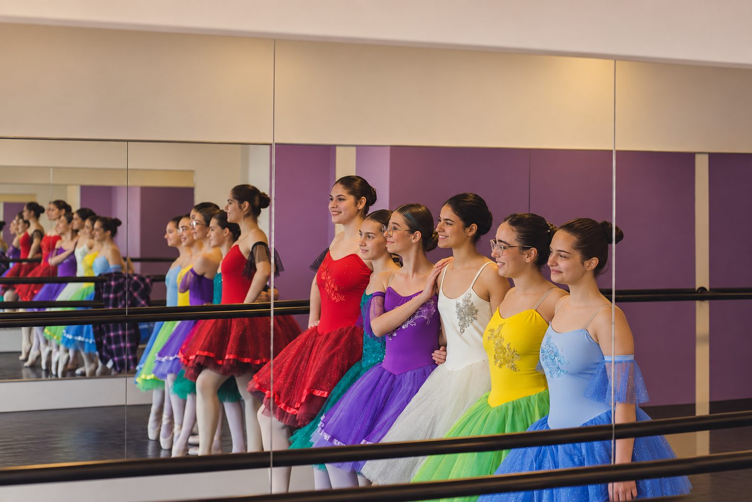 Alunas da Brilhart enfileiradas junto à barra da sala de aula, de figurinos coloridos, refletidas no espelho