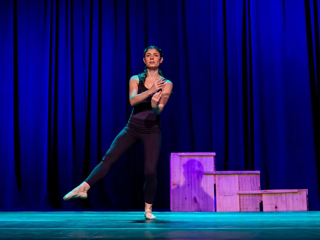 Aluna do Jazz Adulto da Brilhart dançando sozinha no palco, diante de uma cortina azul